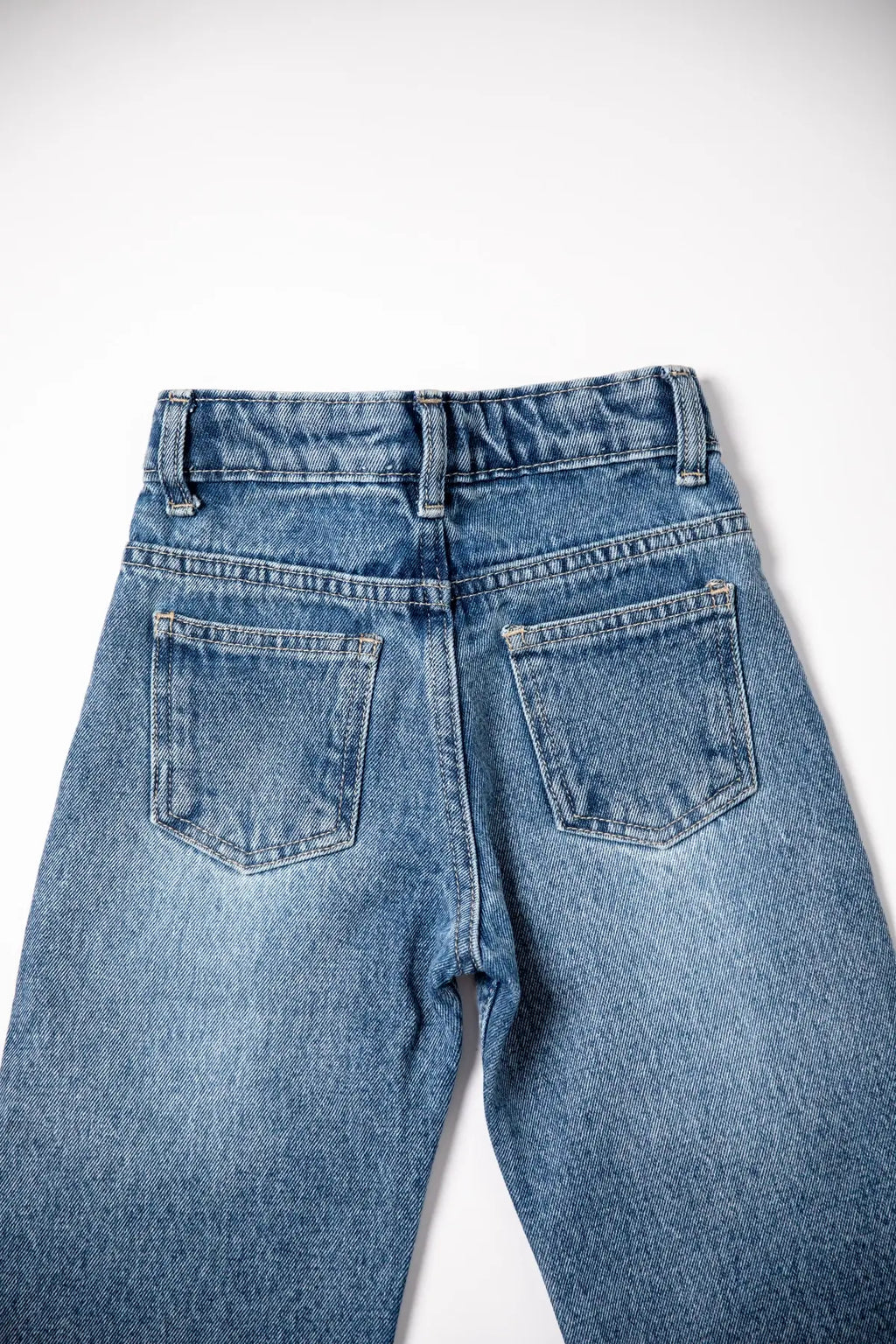 Back view of a pair of blue jeans on a white background