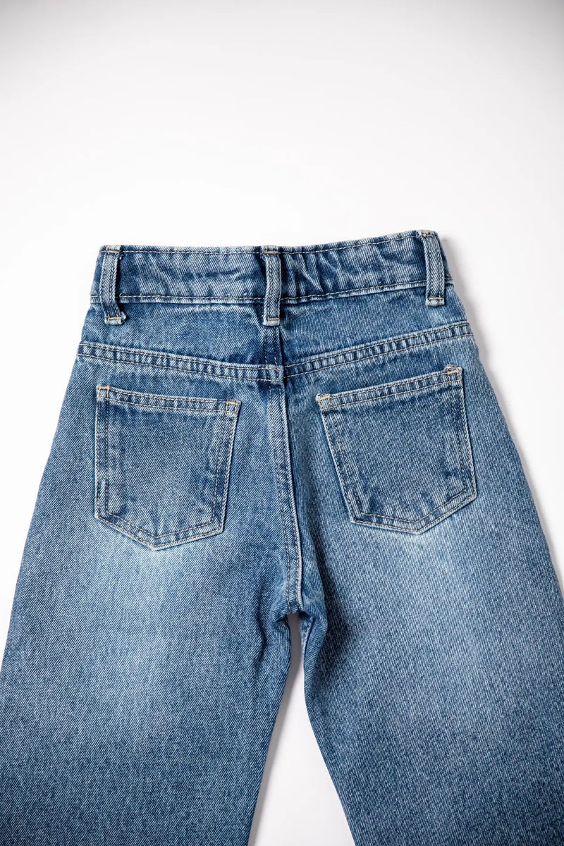 Back view of a pair of blue jeans on a white background