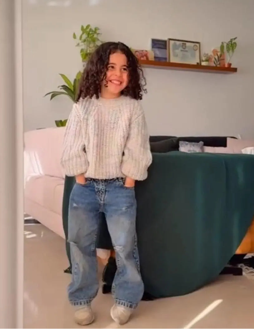 Person standing in a living room with a green couch and white walls.