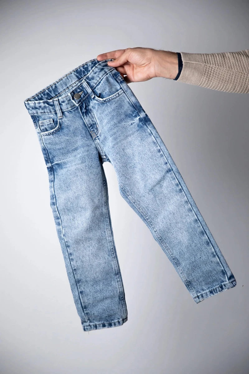 Light blue jeans held by a hand on a gray background