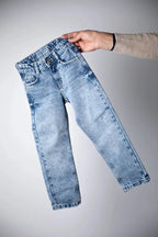 Light blue jeans held by a hand on a gray background