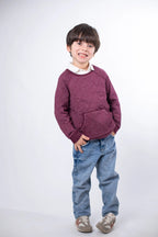 Child wearing a maroon sweater and blue jeans on a white background