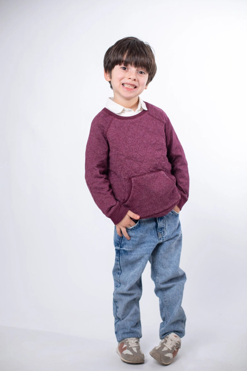 Child wearing a maroon sweater and blue jeans on a white background