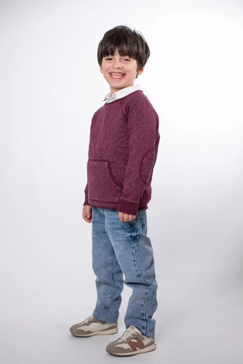 Child wearing a maroon sweater and blue jeans on a white background